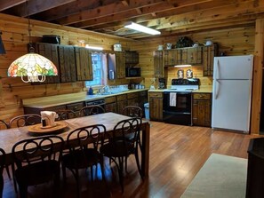 Una cucina in stile baita con tavolo, sedie, frigorifero e pensili in legno.