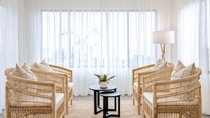 A room with two wicker chairs, a small round table with a plant, and a floor lamp. - Curragudde Cove - Pambula Beach (Pambula Beach)