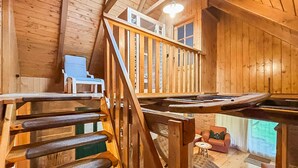 A wooden interior with a wooden staircase, a small seating area with a sofa and a table, and a view through a window. - Stunning home in Velika Jamnicka with sauna (Velika Jamnicka)