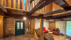 A spacious interior with a high ceiling, exposed wooden beams, a fireplace, and a cozy seating area with a red sofa and a small round table. - Stunning home in Velika Jamnicka with sauna (Velika Jamnicka)