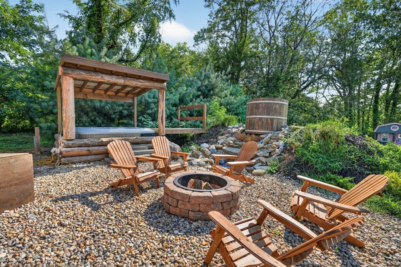 Un espacio al aire libre con sillas Adirondack, un brasero y una pérgola de madera.