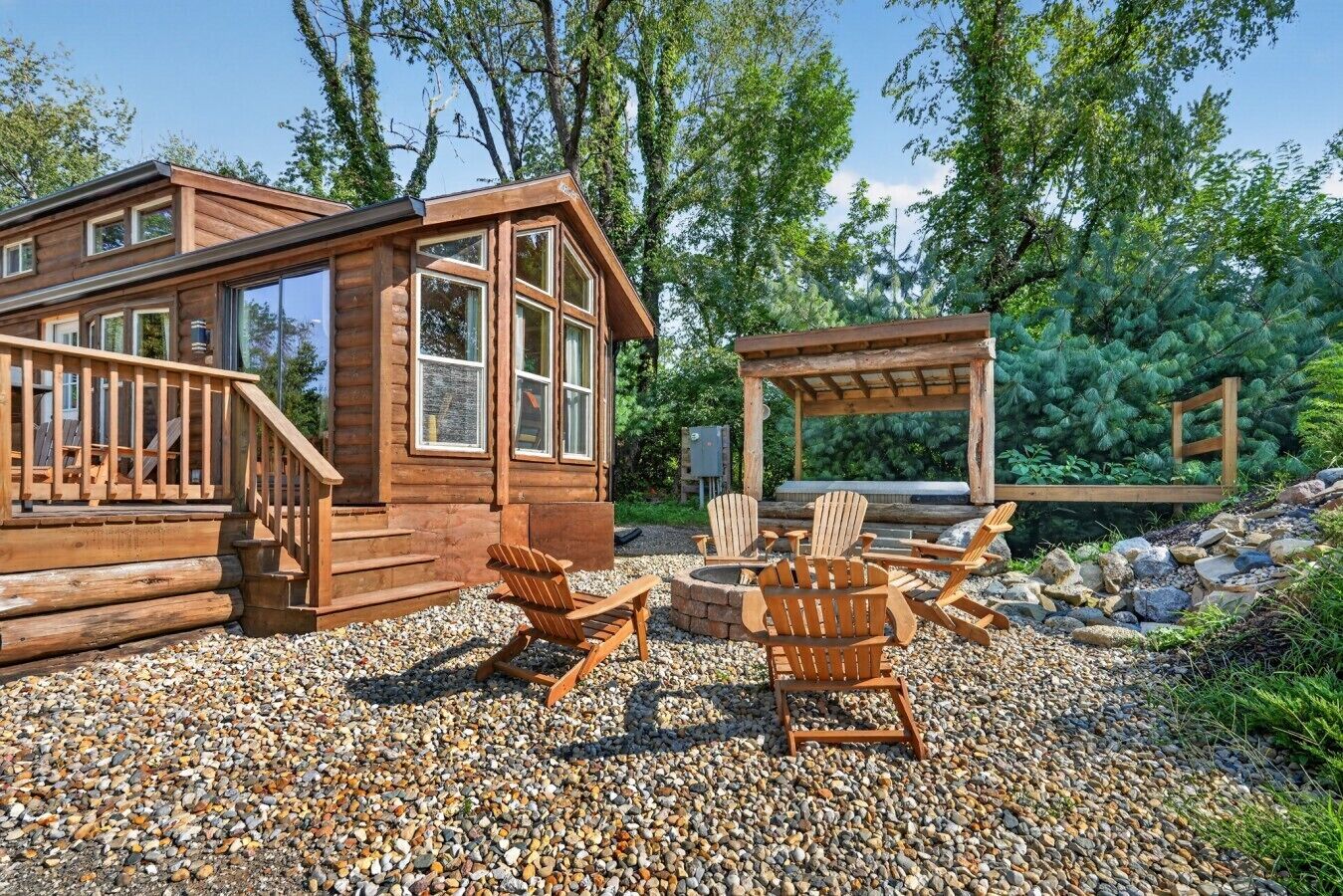 Uma cabana de madeira com varanda, mobiliário de exterior e um espaço para fogueira.