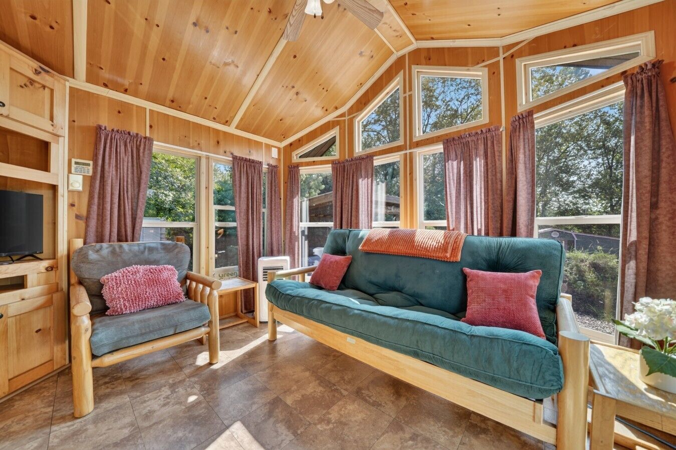 Un intérieur en bois avec un canapé, un fauteuil et un téléviseur.