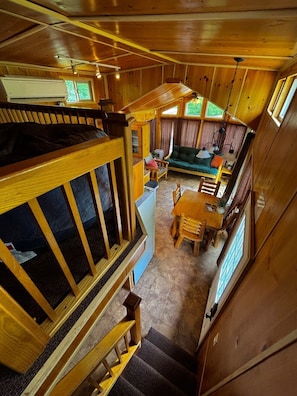 A cabin interior with a loft bedroom, a dining area, and a living room. - Waterfront Bourbon Barrel Cabin (Indianapolis)