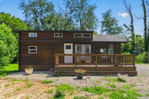 A two-story wooden cabin with a porch and potted plants. - Little Lantern Cabin (Indianapolis)