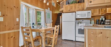 Un interior de madera con una mesa de comedor, sillas, un refrigerador, un microondas y una estufa.