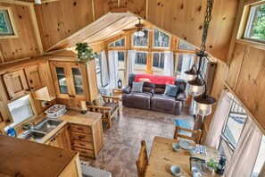 A cabin interior with a kitchen, dining area, and a cozy seating space. - Little Lantern Cabin (Indianapolis)