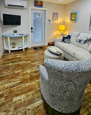 A living room with a sofa, a patterned armchair, a small table with a lamp, and a decorative shelf with starfish. - Spacious 4BR Getaway • Close to Siesta Key (Sarasota)