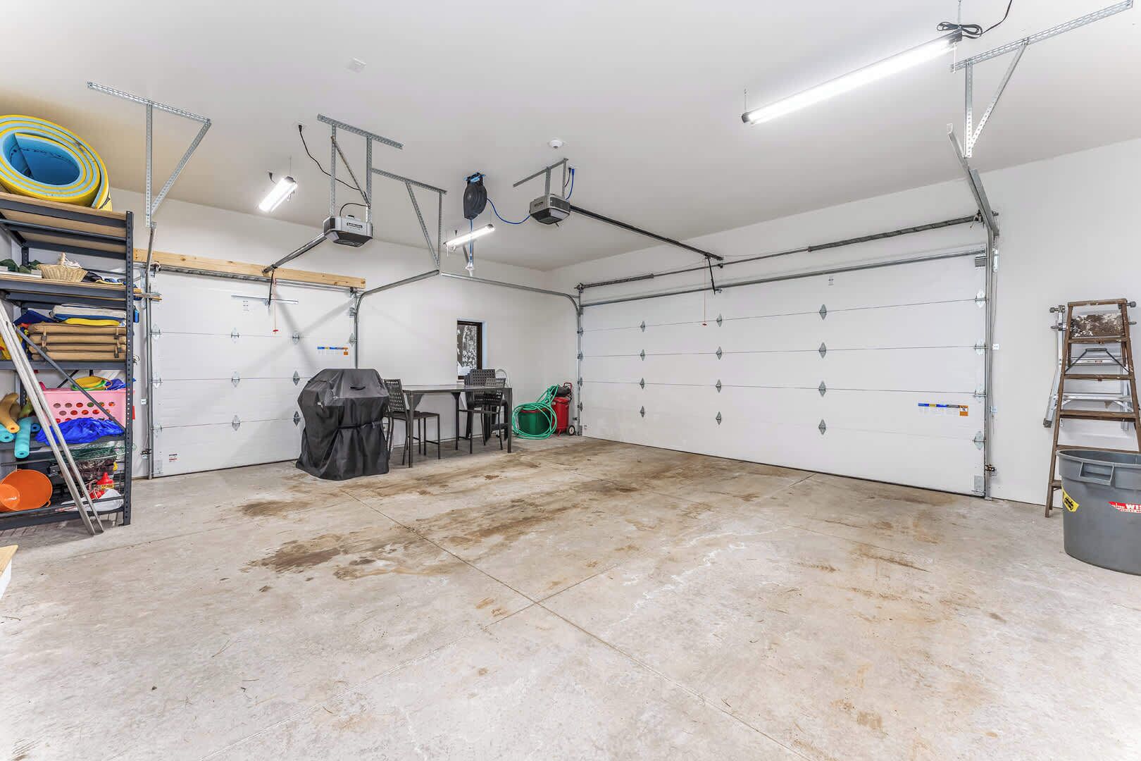 A garage with a workbench, a table, and chairs.