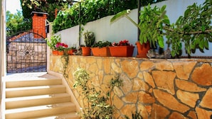 A stone wall with potted plants and a metal gate.