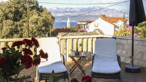 A terrace with two chairs and a table, overlooking a mountainous landscape and a body of water. - Stunning apartment in Supetar with WiFi (Supetar)