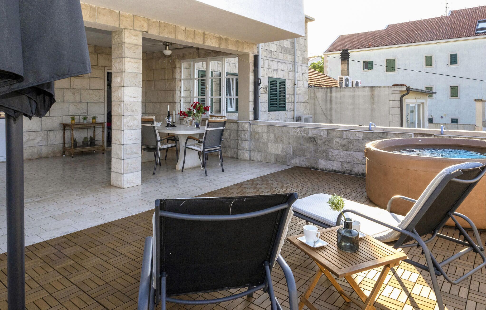 Ein Balkon mit Tisch und Stühlen, einem Whirlpool und Blick auf die Stadtlandschaft.