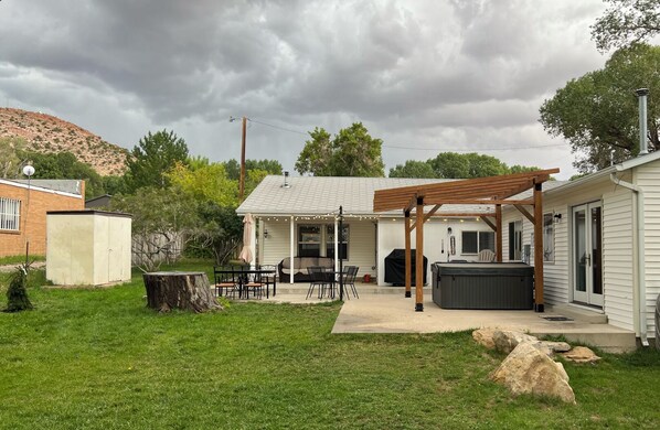 A backyard with a covered patio, outdoor seating, a hot tub, and a shed. - Cozy Christmas Retreat - Hot Tub, Fireplaces, Sleeps 11 Near Flaming Gorge (Manila)