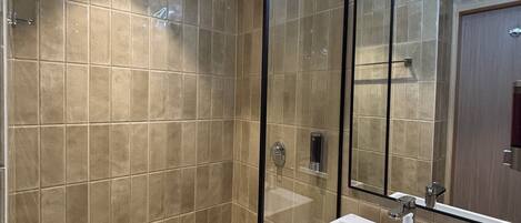 Un baño moderno con un espejo grande, un lavabo blanco y paredes con azulejos.