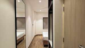 A narrow hallway with two beds, wooden flooring, and a mirrored wall. - Round D Clock (New Delhi)