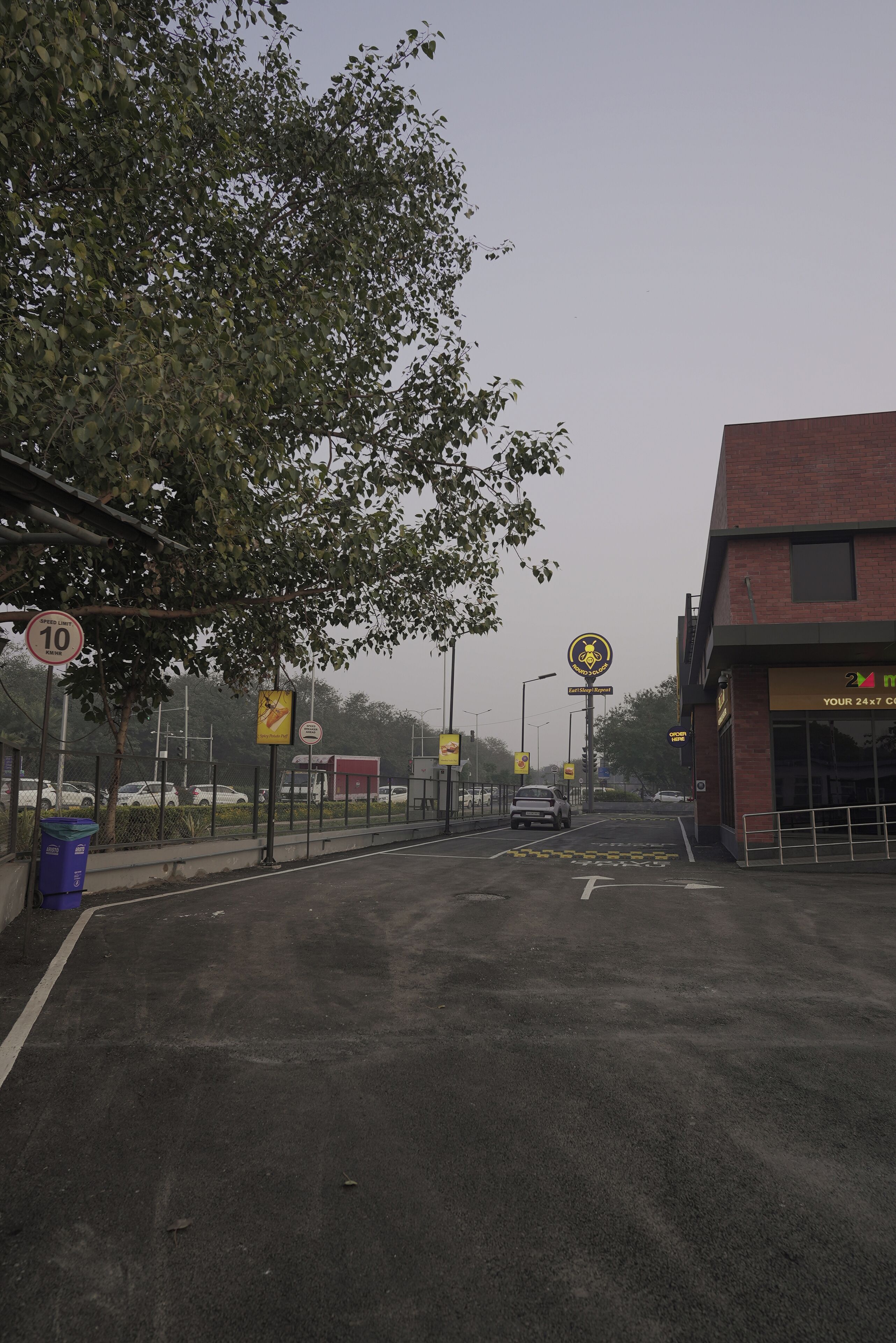 Une route avec un panneau indiquant la vitesse maximale autorisée, un panneau de passage pour piétons et un bâtiment sur lequel est affiché un panneau indiquant : « Service clientèle disponible 24 heures sur 24, 7 jours sur 7 ».