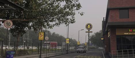 Une route avec un panneau indiquant la vitesse maximale autorisée, un panneau de passage pour piétons et un bâtiment sur lequel est affiché un panneau indiquant : « Service clientèle disponible 24 heures sur 24, 7 jours sur 7 ».