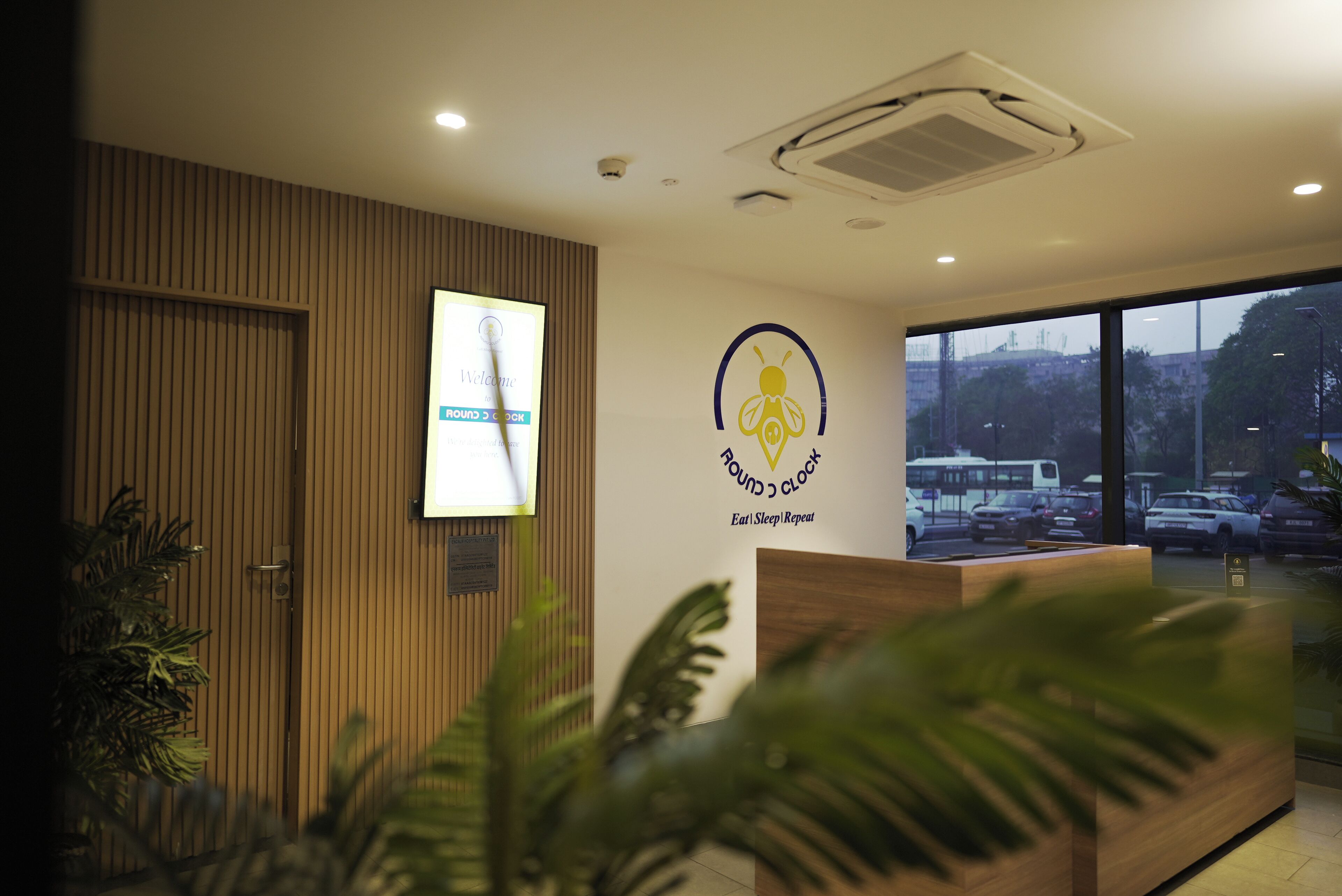 A reception desk with a logo, a clock, and a view of the street outside.