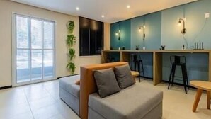 Una sala de estar moderna con un sofá gris, una mesa de centro de madera y un comedor con una pequeña mesa y sillas.