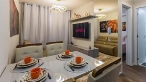 Una sala de estar moderna con comedor, un televisor de pantalla plana y un sofá.