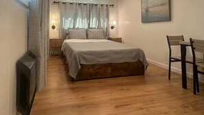 A bedroom with a large bed, two bedside tables with lamps, a wooden chair, and a painting on the wall. - Monterey Bay Hideaway (Seaside)