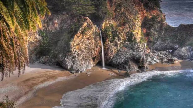 A coastal landscape with a waterfall, beach, and ocean. - Monterey Bay Hideaway (Seaside)