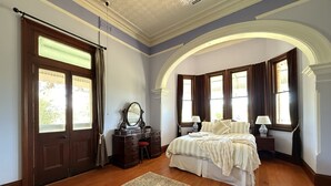A bedroom with a large bed, a dresser, a mirror, and a rug. - Kalimna Homestead, Historic Stays, Hunter Valley (Paterson)