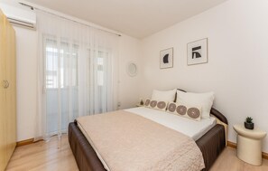 A bedroom with a bed, a bedside table, a small potted plant, and a window with sheer curtains. - Cozy apartment in Vir with WiFi (Vir)