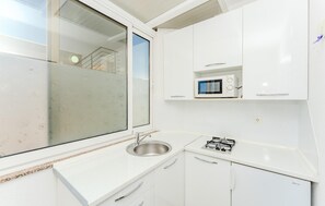 A compact kitchen with a stainless steel sink, a microwave, and a gas stove.