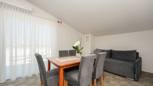 A dining area with a table, chairs, a potted plant, and a grey sofa. - Stunning apartment in Vir with WiFi (Vir)