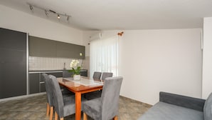 A modern kitchen with grey cabinets, a dining table with four chairs, and a grey sofa. - Stunning apartment in Vir with WiFi (Vir)