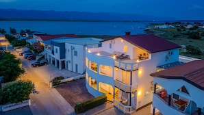 A multi-story building with a pool, surrounded by parked cars and a view of a body of water. - Stunning apartment in Vir with WiFi (Vir)
