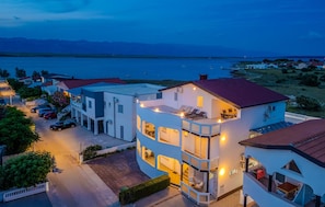 A multi-story building with a pool, surrounded by parked cars and a view of a body of water. - Stunning apartment in Vir with WiFi (Vir)