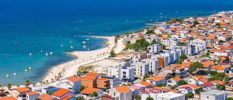 A coastal town with a beach, residential buildings, and boats on the water.
