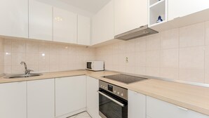 Una cucina moderna con pensili bianchi, un lavello in acciaio inossidabile, un forno a microonde e un forno.