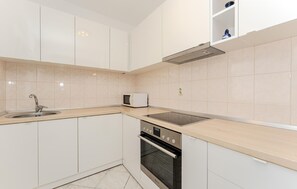 A modern kitchen with white cabinets, a stainless steel sink, a microwave, and an oven. - Amazing apartment in Vir with WiFi (Vir)