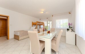 A hotel room with a bunk bed, a glass dining table with chairs, a small kitchen area, and a window with curtains. - Amazing apartment in Vir with WiFi (Vir)