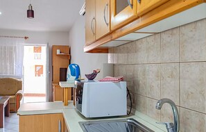 A kitchen with wooden cabinets, a white toaster, a kettle, and a sink.