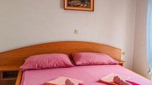A bedroom with a wooden headboard, pink bedding, and a painting on the wall. - Awesome apartment in Vir with WiFi (Vir)