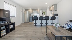 Un appartement moderne comprenant une cuisine, un coin repas et un téléviseur situé à gauche.