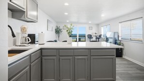 Une cuisine moderne avec des meubles gris, un grand îlot central et une vue sur l’extérieur.