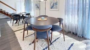 A modern dining area with a round table, blue upholstered chairs, a fluffy white rug, and a staircase in the background. - #11 Modern 2-BR sanctuary walk to shops & beach (Santa Monica)