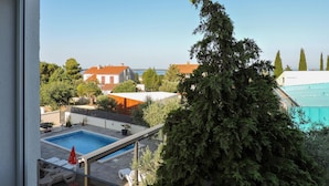 A residential area with a swimming pool, a large tree, and houses with red roofs. - Nice apartment in Peroj with swimming pool (Peroj)