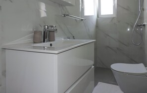Ein modernes Badezimmer mit Waschtisch, Toilette und Duschbereich.