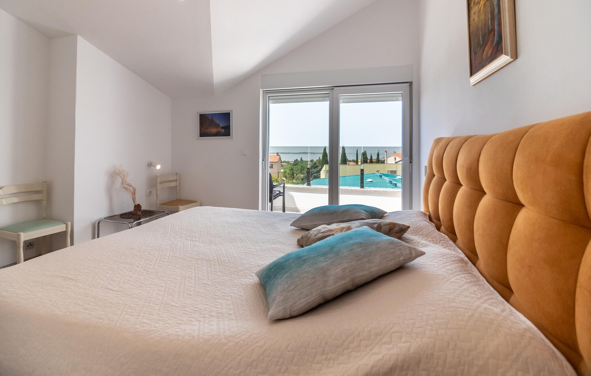 Een slaapkamer met een groot bed, uitzicht op de zee en een balkon.