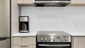 A kitchen with a stainless steel stove, a coffee maker, and a microwave above it.