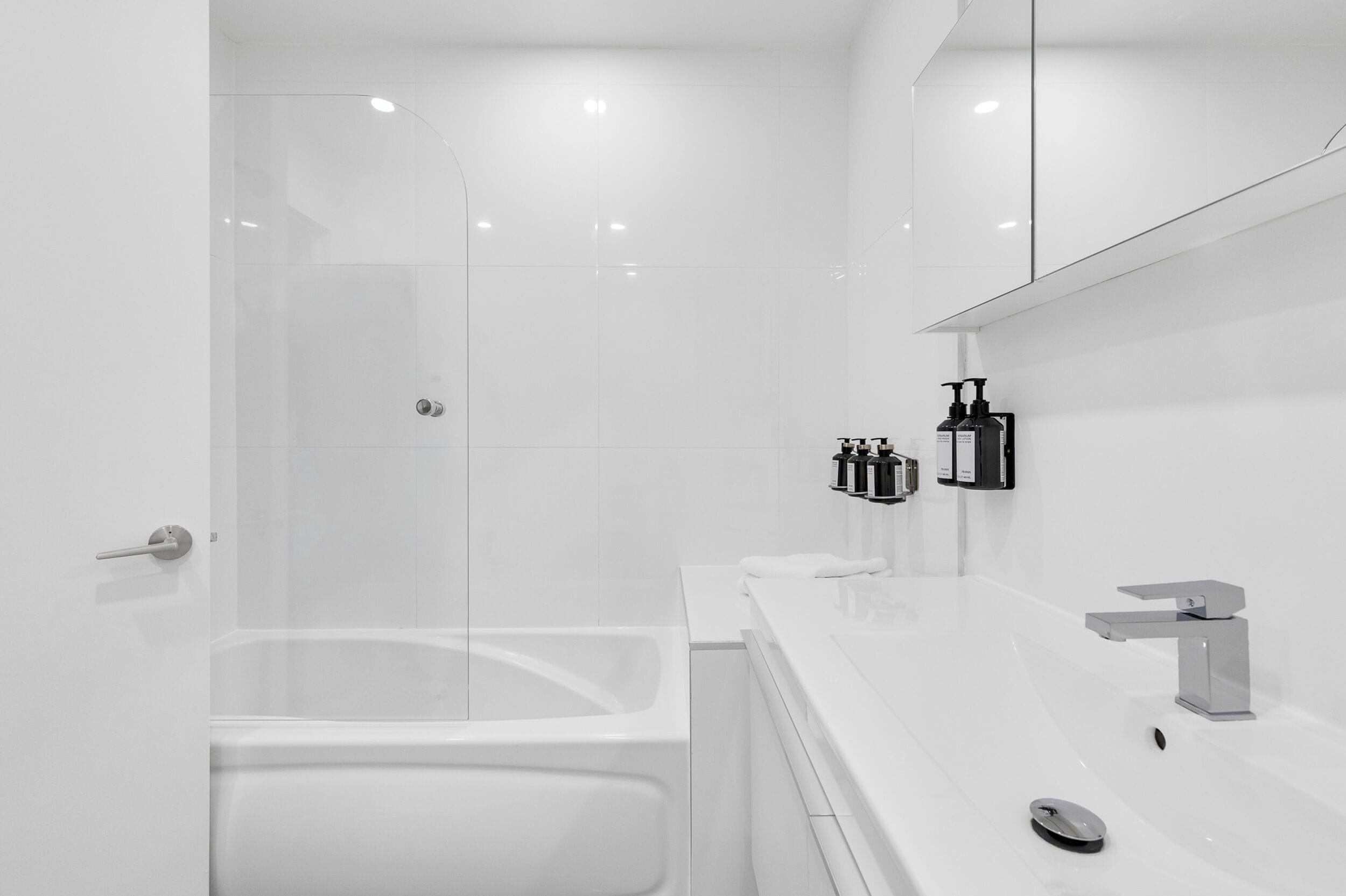 Une salle de bain moderne avec une douche à parois de verre, un lavabo blanc et un grand miroir.