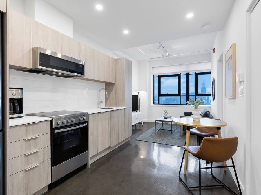 Una cocina moderna con electrodomésticos de acero inoxidable, armarios de madera y una zona de comedor con mesa y sillas.