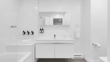 A modern bathroom with a white vanity, a bathtub, a shower, and a toilet.