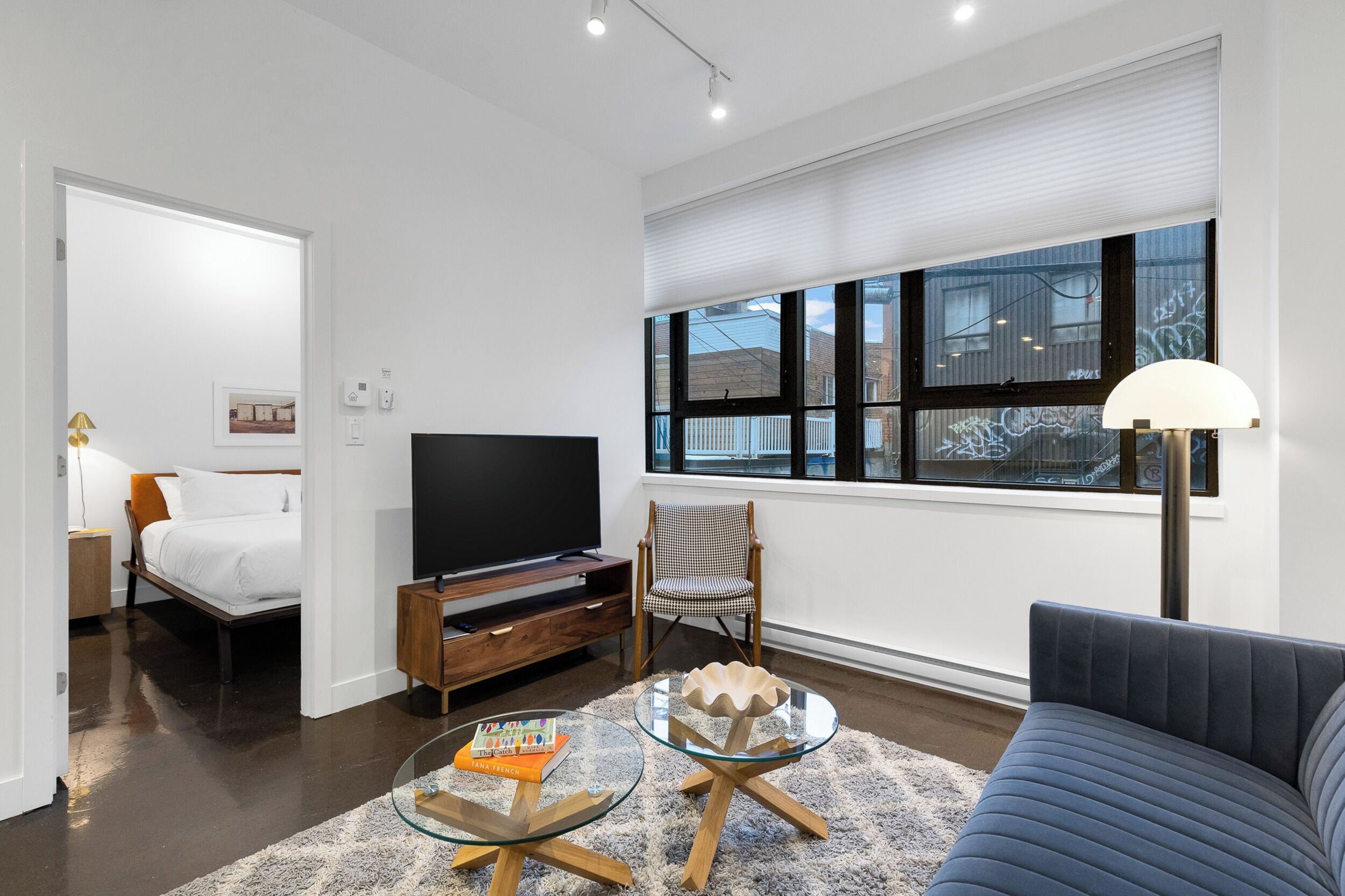 A modern living room with a bed, TV, and seating area.